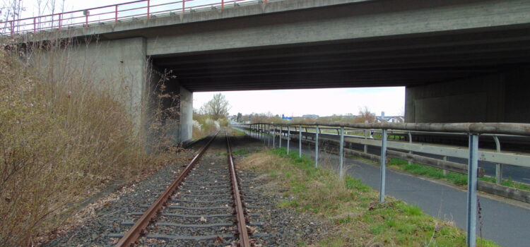 Die Trasse der Steigerwaldbahn führt zwischen Gochsheim und Sennfeld neben einem Radweg und einer Straße unter der Autobahnbrücke hindurch.