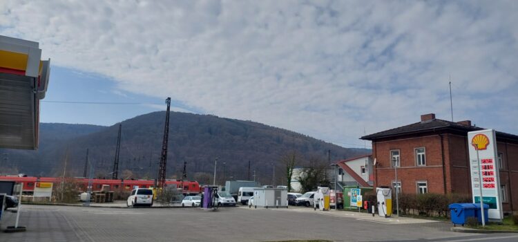 Scherbenhaufen der letzten Legislatur und berechtigte Tankwut: Mobilitätsarmut politisch selbstgemacht Bild: Tankstelle mit Benzinpreisen über 2 €/l; dahinter elektrische Triebzüge